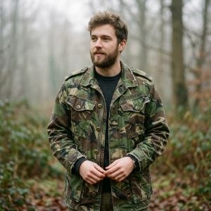 Close-up of stacked British military surplus field jackets and trousers featuring DPM and MTP patterns.