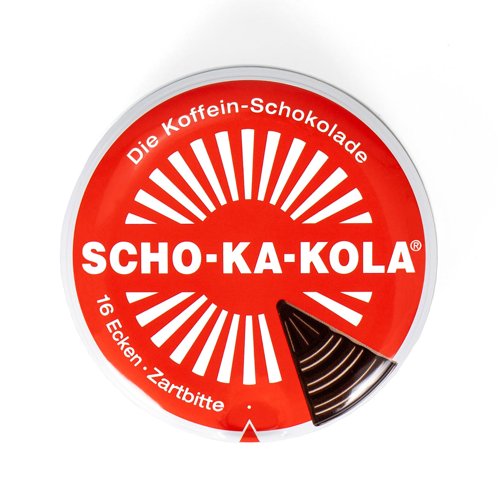 Top-down view of the classic Scho-Ka-Kola energy chocolate tin featuring the distinctive sunburst graphic design.