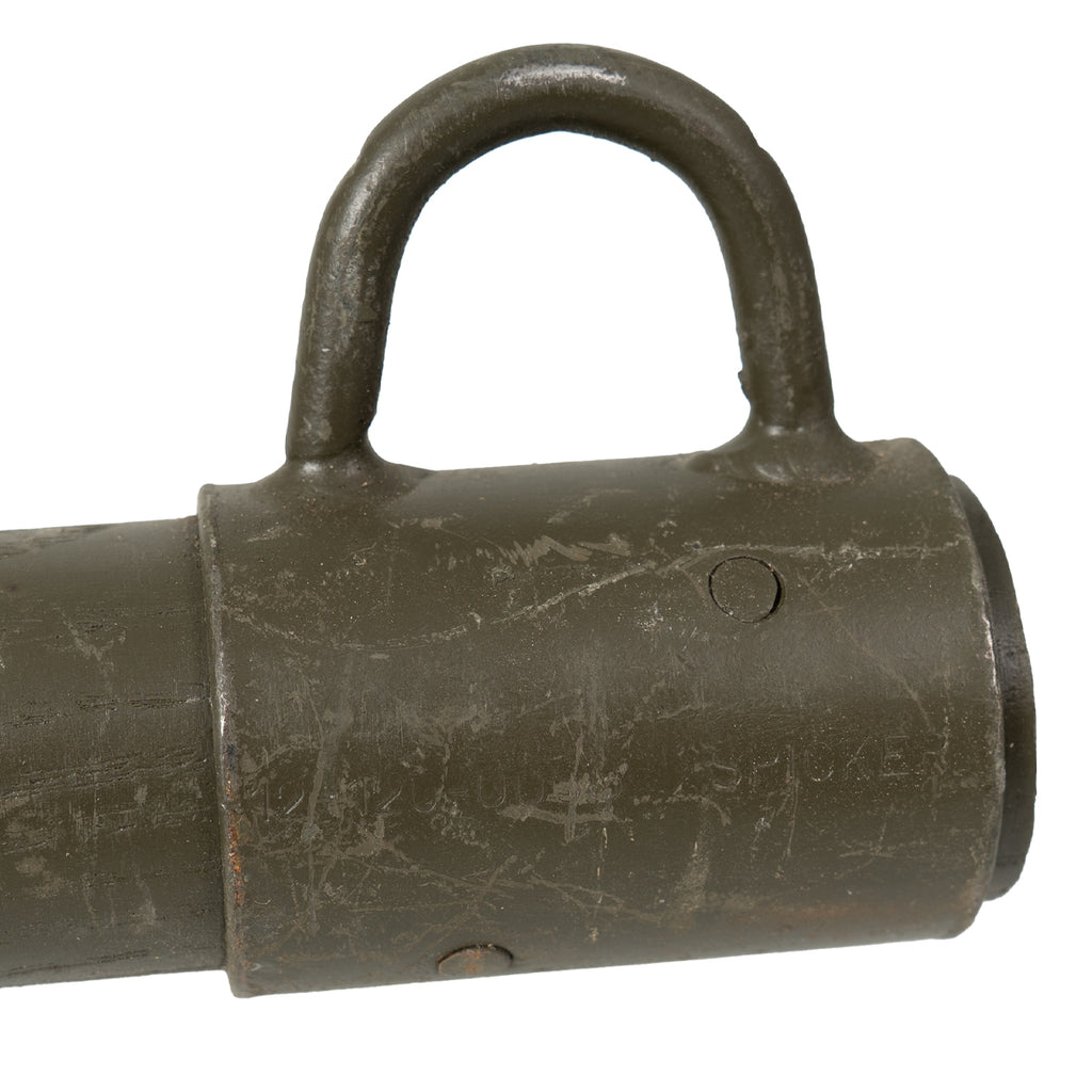 Close-up of the steel collar and guy line ring on a vintage Bundeswehr wooden tent stake showing weathered olive paint.