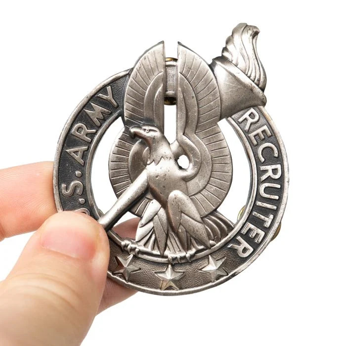 Close-up of US Army Recruiter Badge held in hand showing scale and silver finish