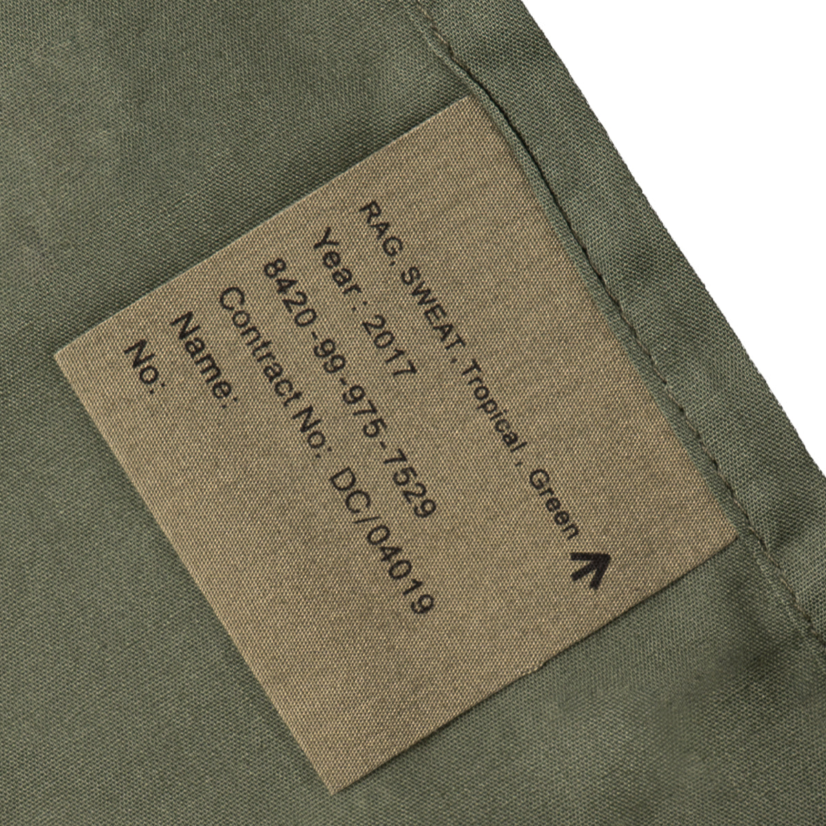 Close-up of military issue tag on 2017 British Army sweat rag showing NSN 8420-99-975-7529 and tropical green fabric.