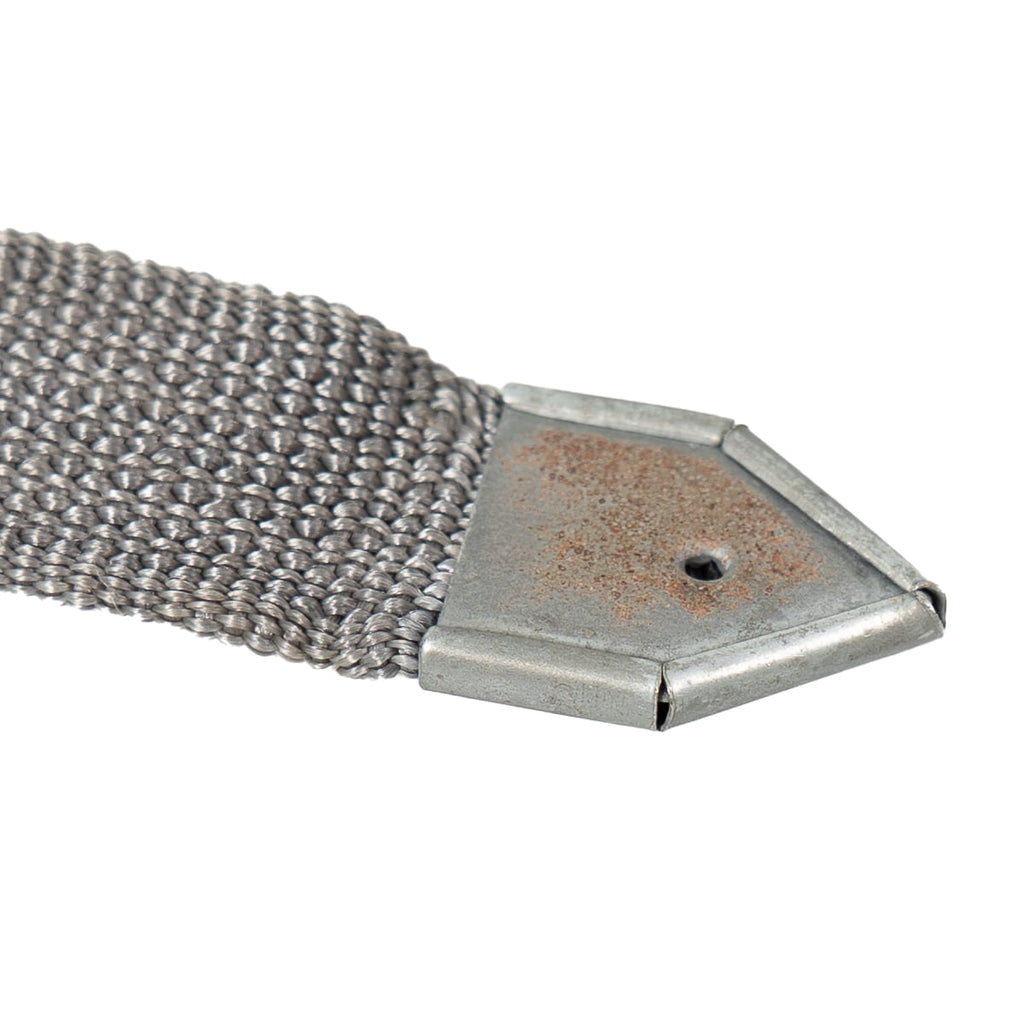 Detail of the pointed metal end tip on an original NVA Rödelriemen strap, showing authentic cold war field-used condition.