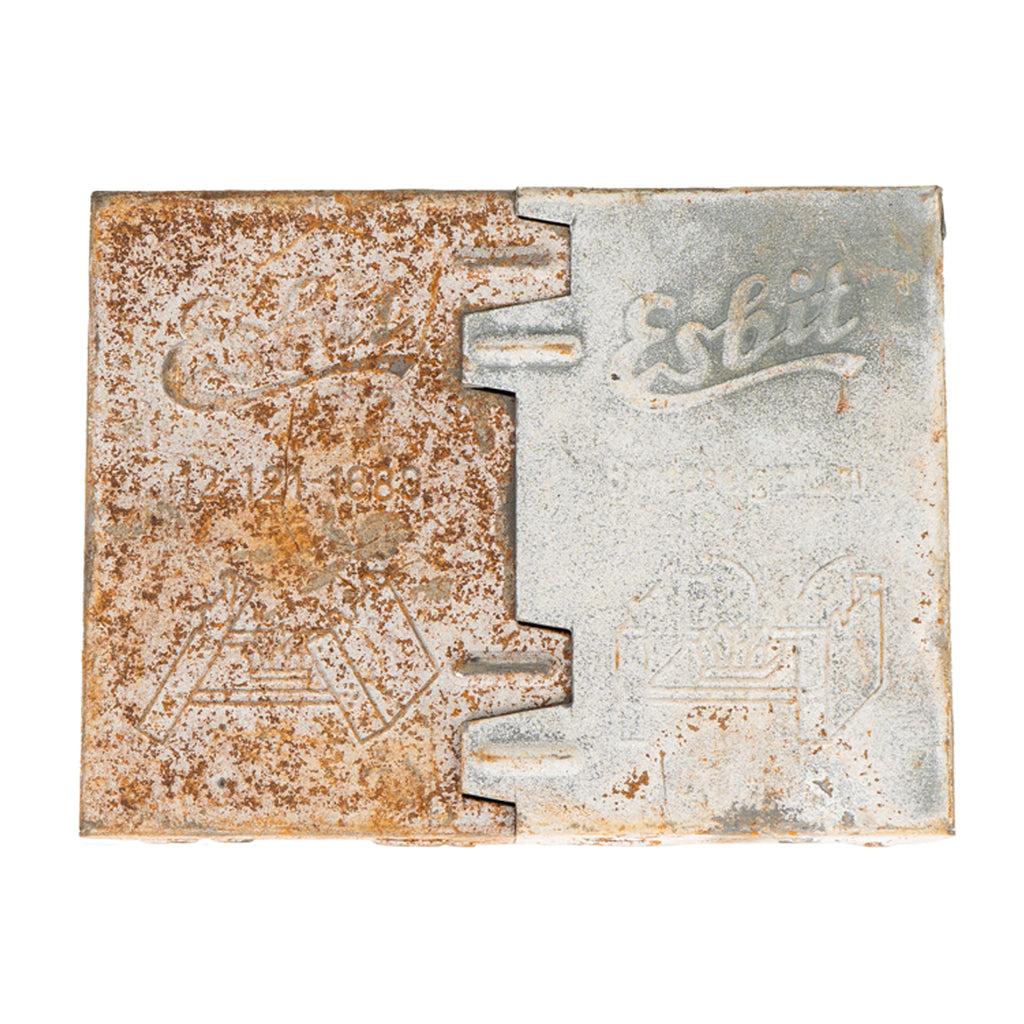 A front view of a compact, folded metal Esbit stove with visible patina and German military markings.