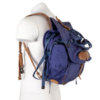 Side profile of a Romanian Army blue canvas rucksack featuring leather straps and side pouch on a display mannequin.