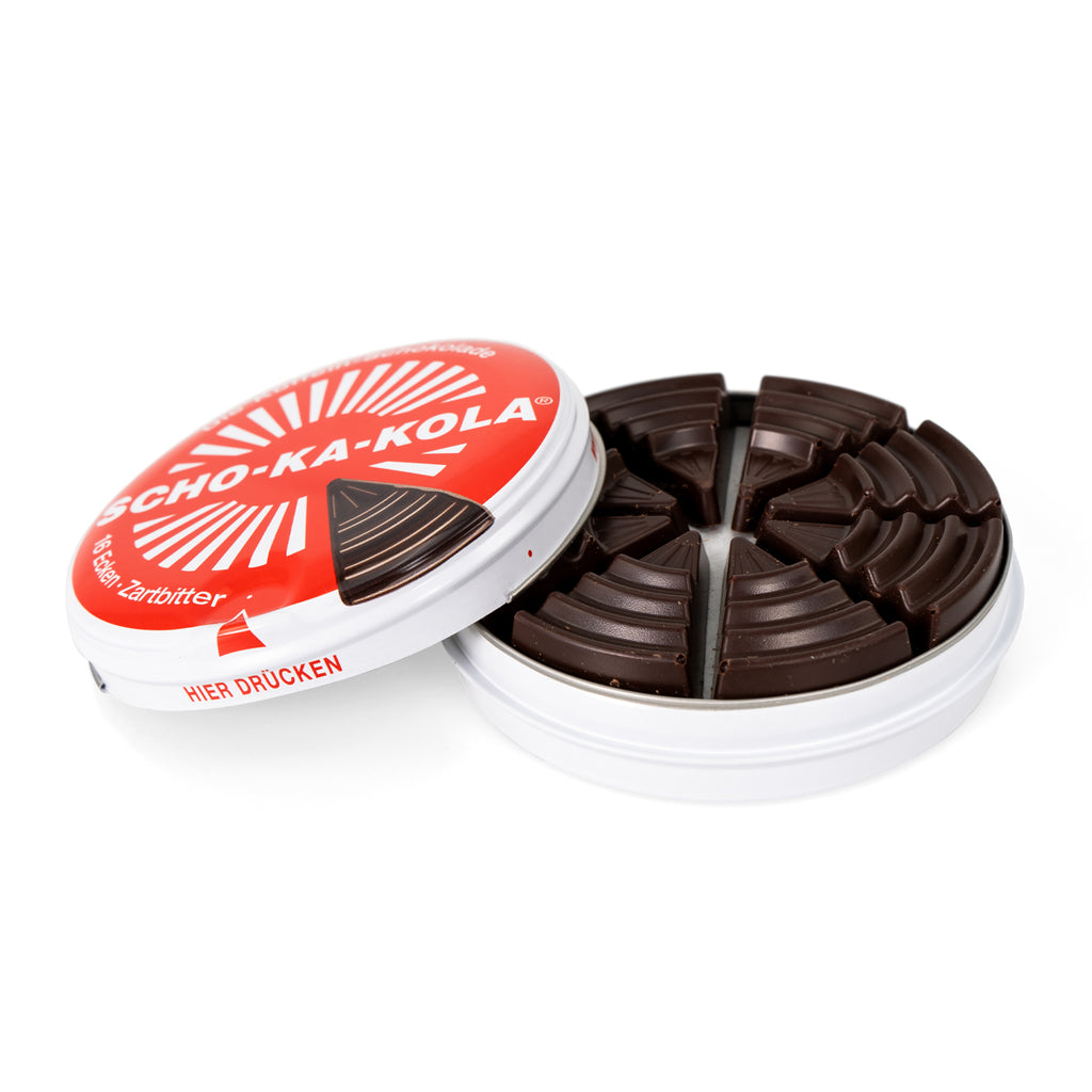 Open metal tin of Scho-Ka-Kola dark chocolate revealing 16 individual bittersweet cocoa wedges arranged in a circular pattern.