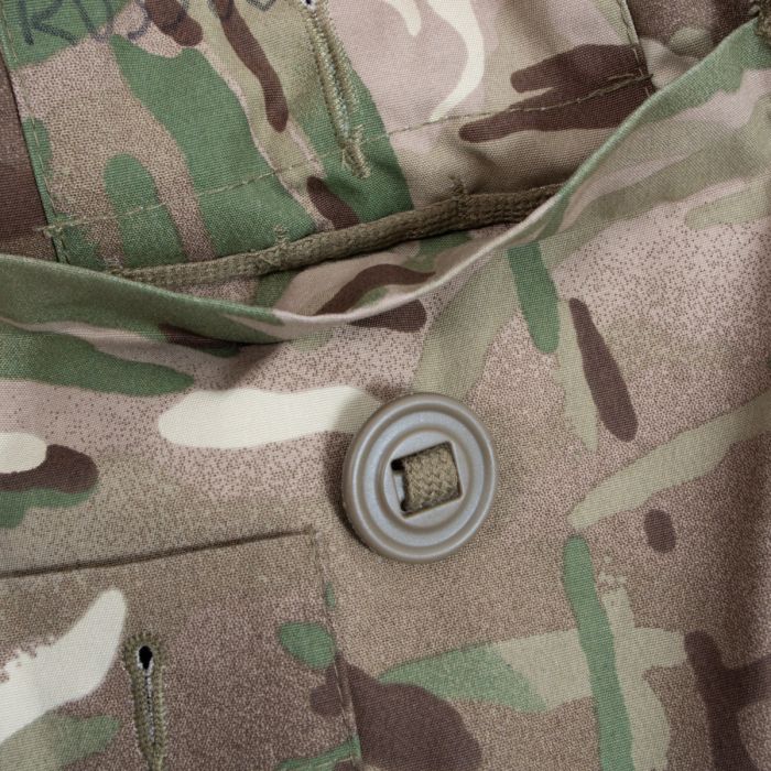 Detailed view of lower bellows pocket flap, slotted button on webbing tape, and MTP camouflage weave