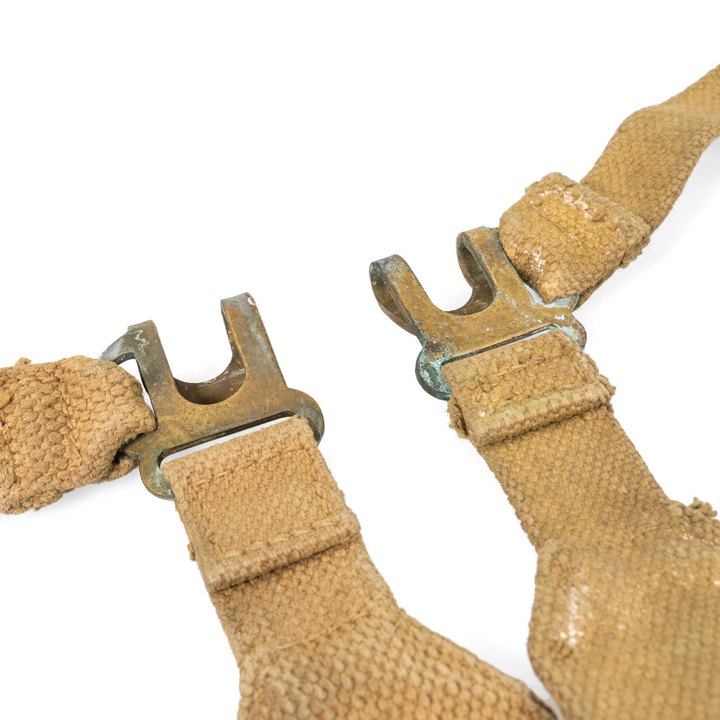 Close-up of the brass attachment hooks on British Army 37 Pattern L-straps, showing authentic post-war surplus patina and metal wear.