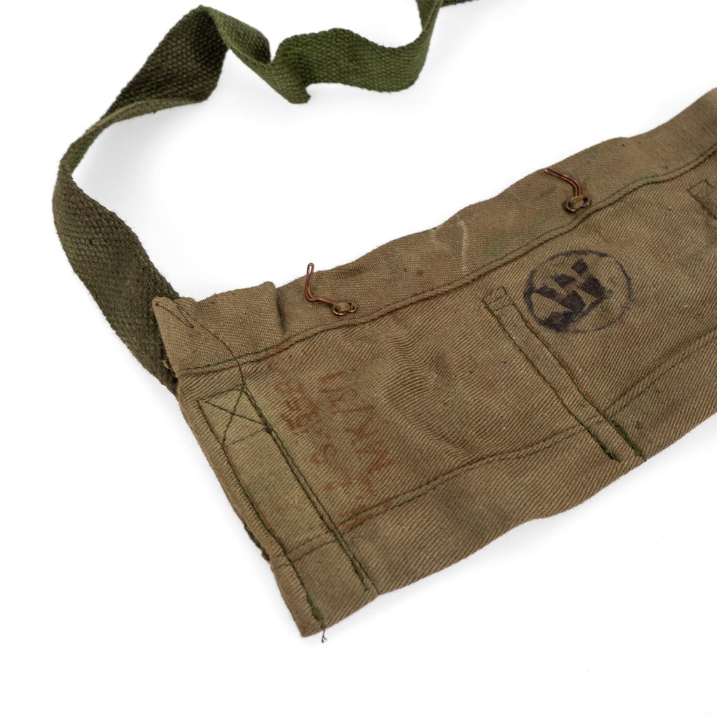 Detail of the side section of a vintage British Army bandolier showing metal hooks and authentic service markings.