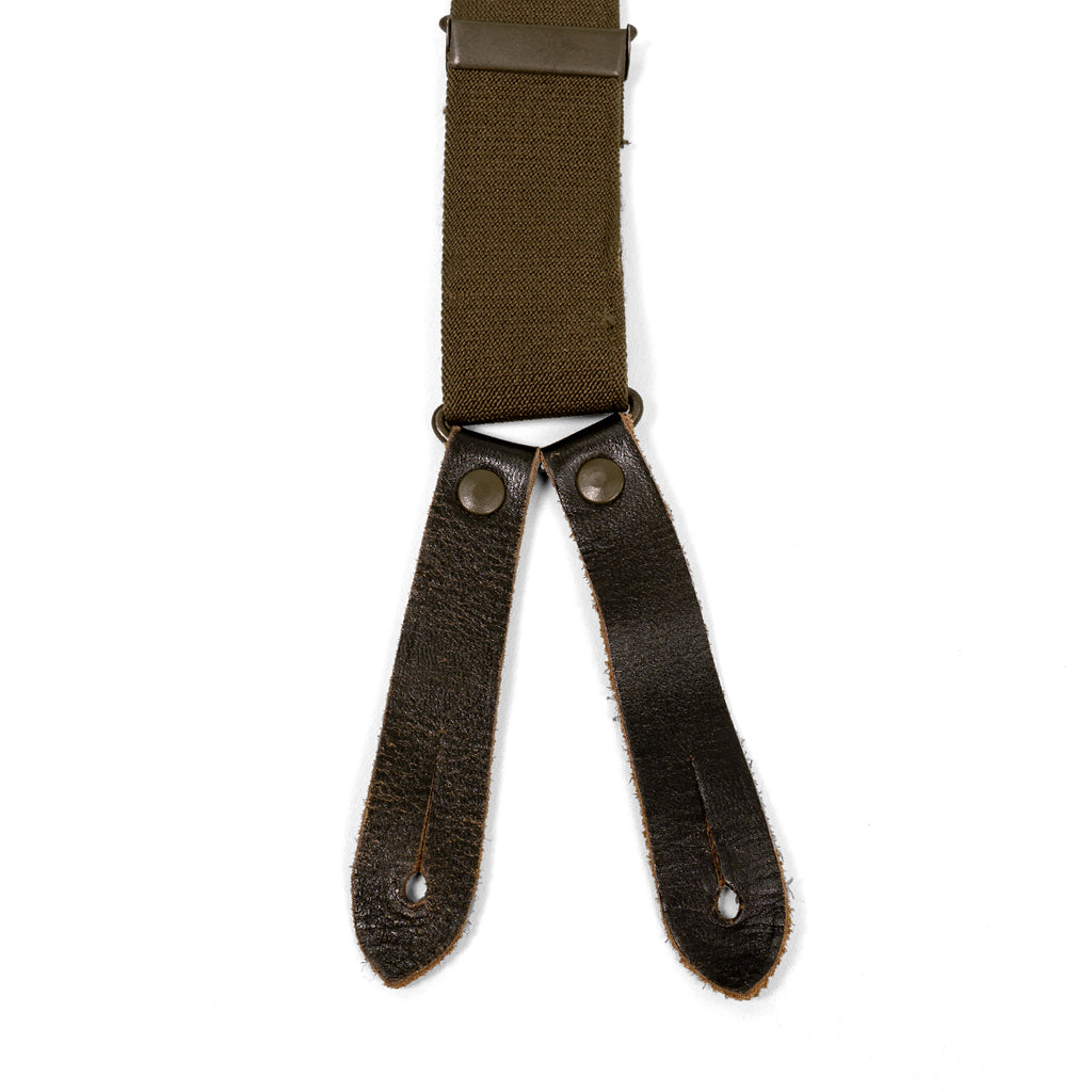 Detail of German Army brace attachment point with dark brown leather tabs, metal rivets, and buttonholes on olive green elastic webbing.