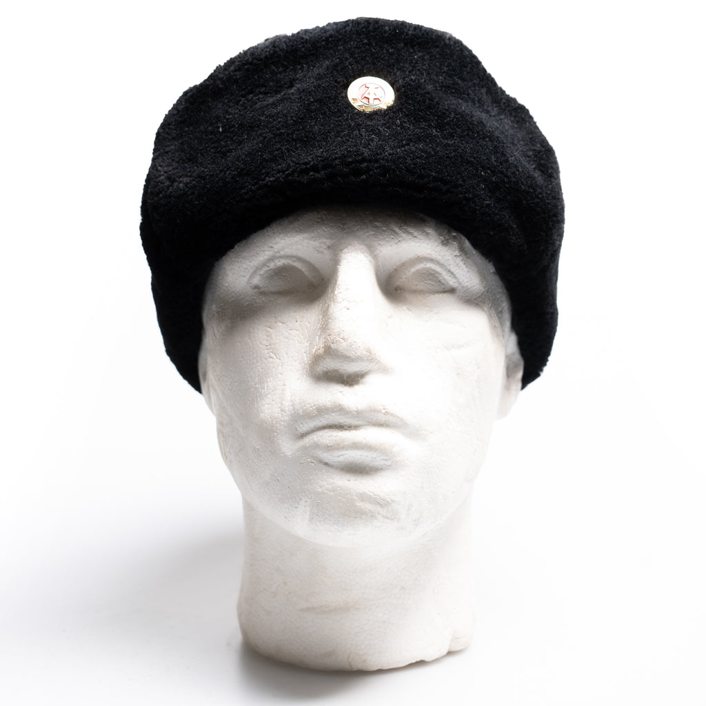 Front view of an authentic East German military Ushanka hat with ear flaps secured upward on a mannequin.