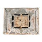 The underside of a vintage Esbit burner showing ventilation slots and signs of heavy outdoor use.