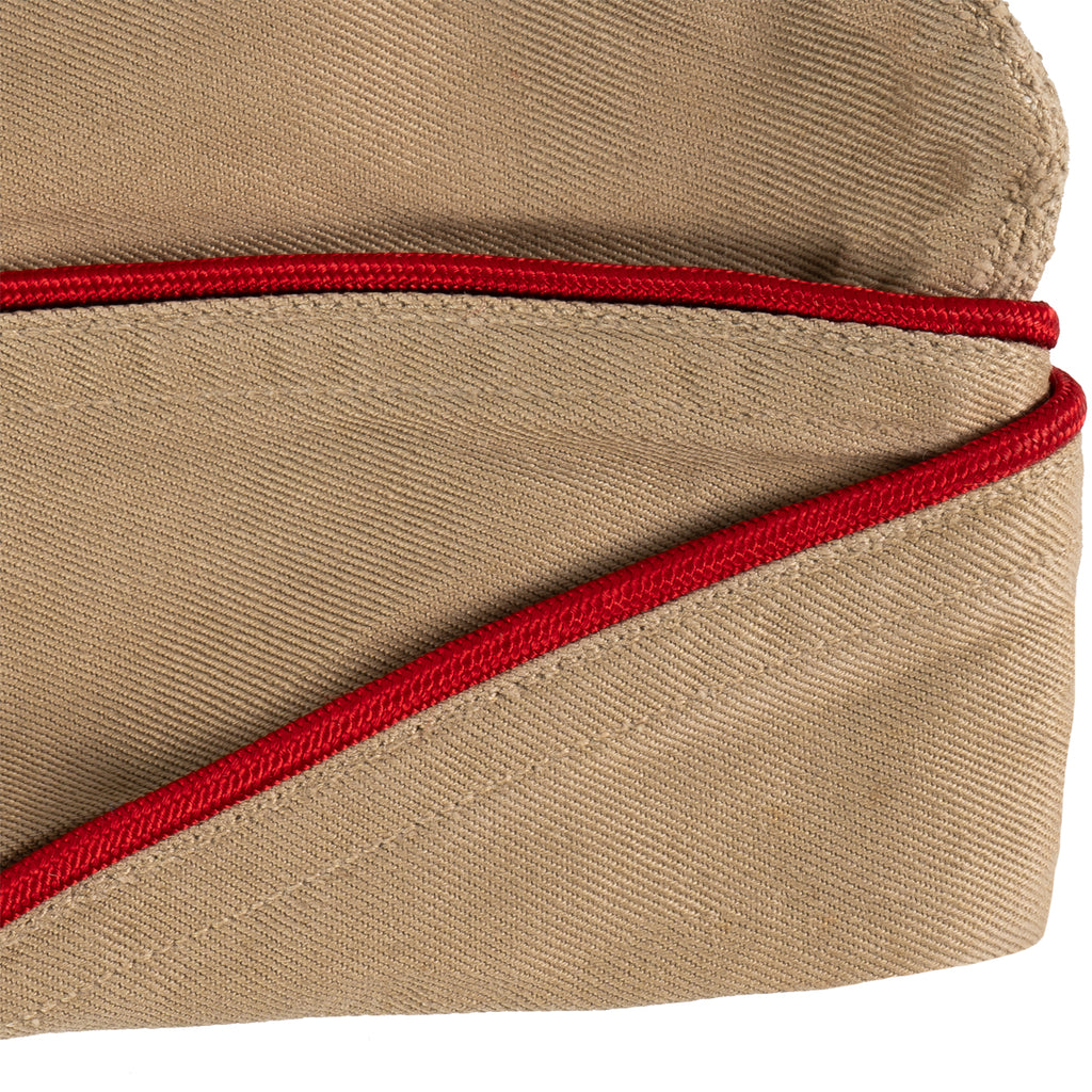 Close-up detail of a vintage US Army Khaki Garrison Cap showing the texture of the cotton twill and red piping trim.