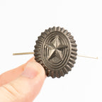 Metallic star-shaped hair clip held by a hand against a white background