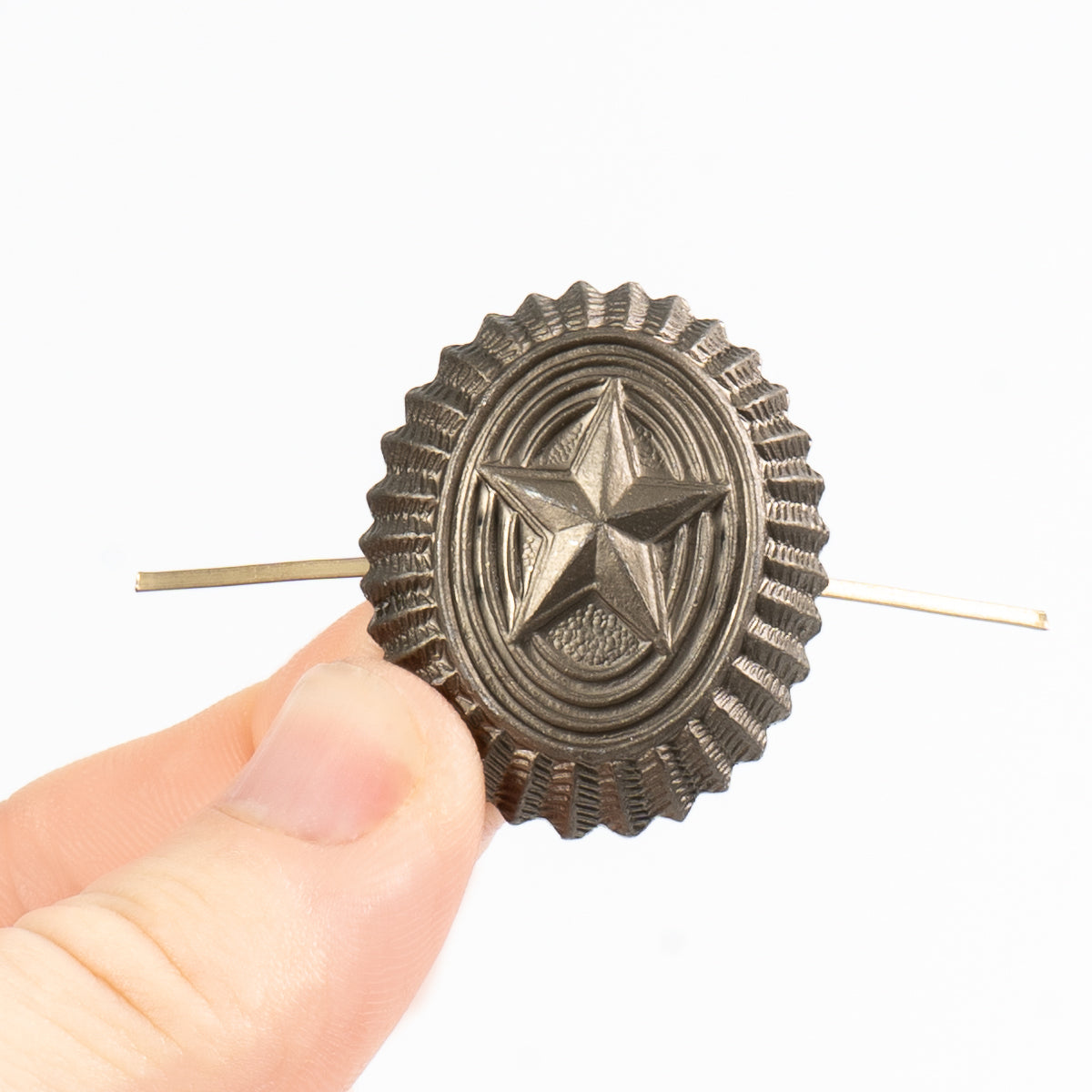 Metallic star-shaped hair clip held by a hand against a white background