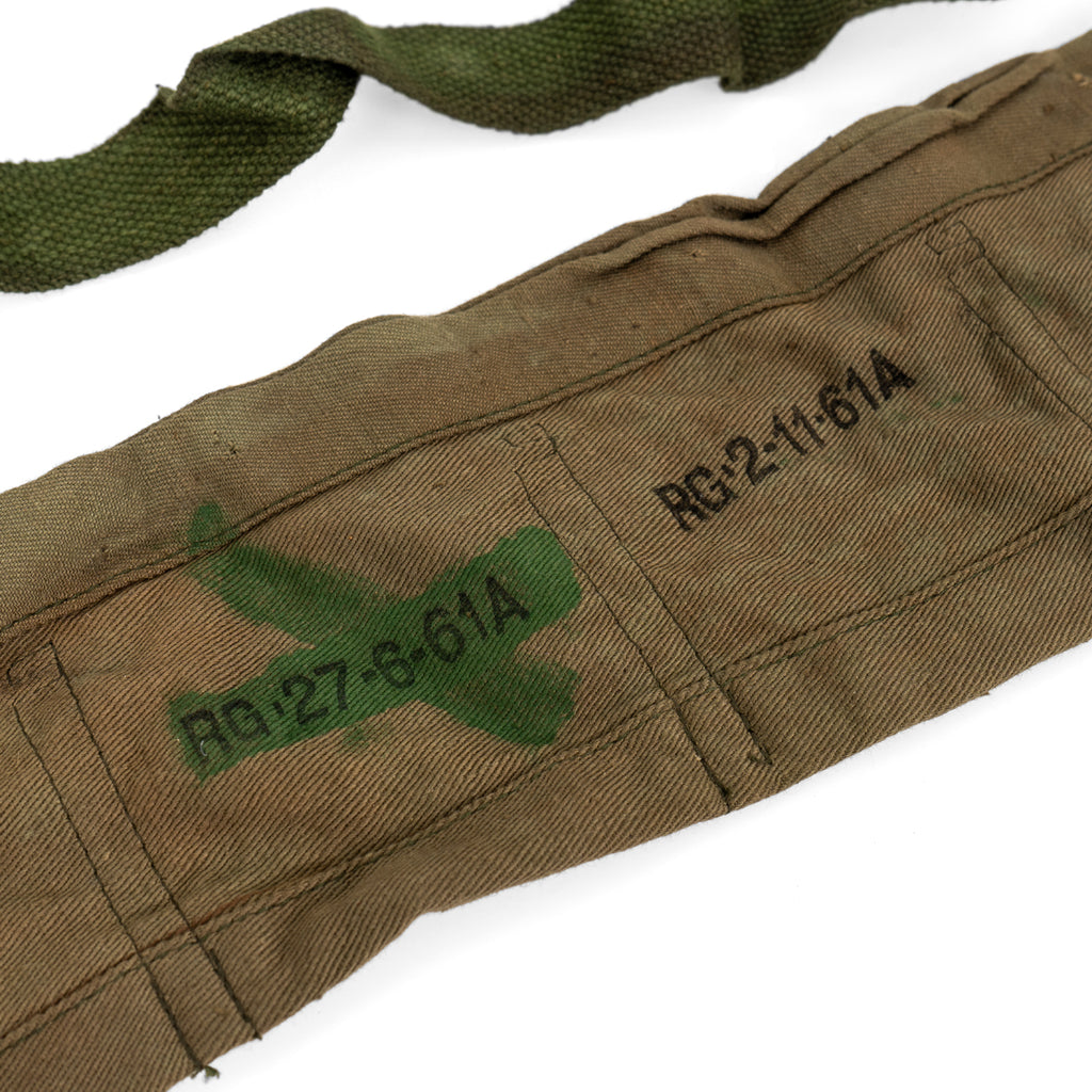 Macro view of military inspection markings and a green cross on a durable tan cotton .303 ammo bandolier.