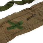 Macro view of military inspection markings and a green cross on a durable tan cotton .303 ammo bandolier.
