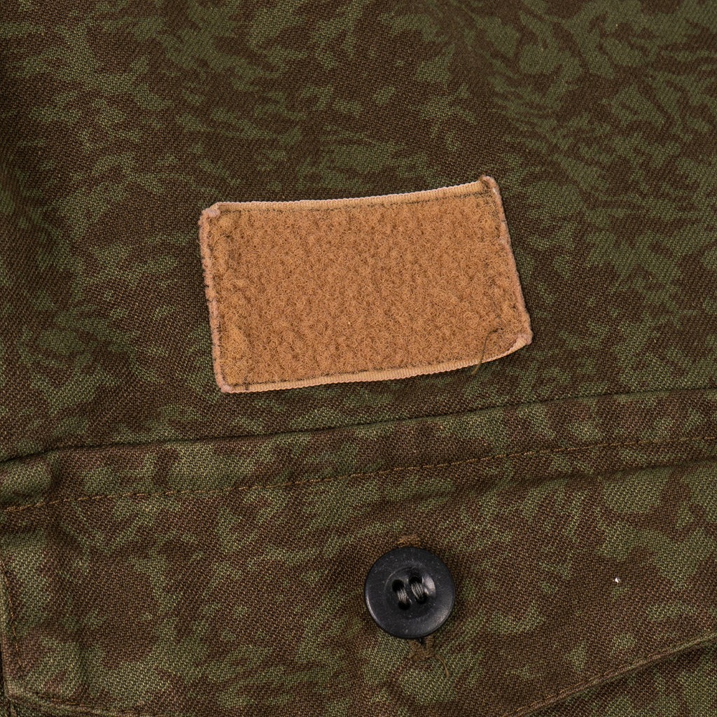 Close-up of the chest area of the M92 field jacket featuring a tan hook-and-loop patch and button-secured pocket flap.