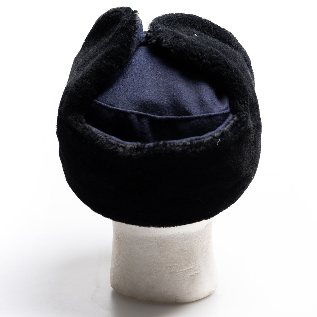 Rear view of a navy blue surplus East German Army Ushanka hat, showcasing the durable construction and folded ear flaps.