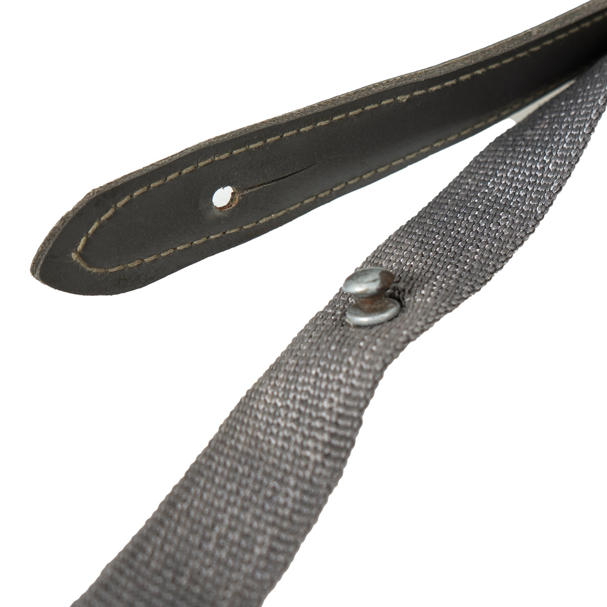 Macro view of the NVA strap's attachment mechanism, featuring the stitched Lederol tab and the metal mushroom stud used in East German battle packs.