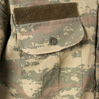 Close-up of the military field shirt chest pocket detail, showing the buttoned flap closure and a green Velcro strip for identification or insignia attachment.