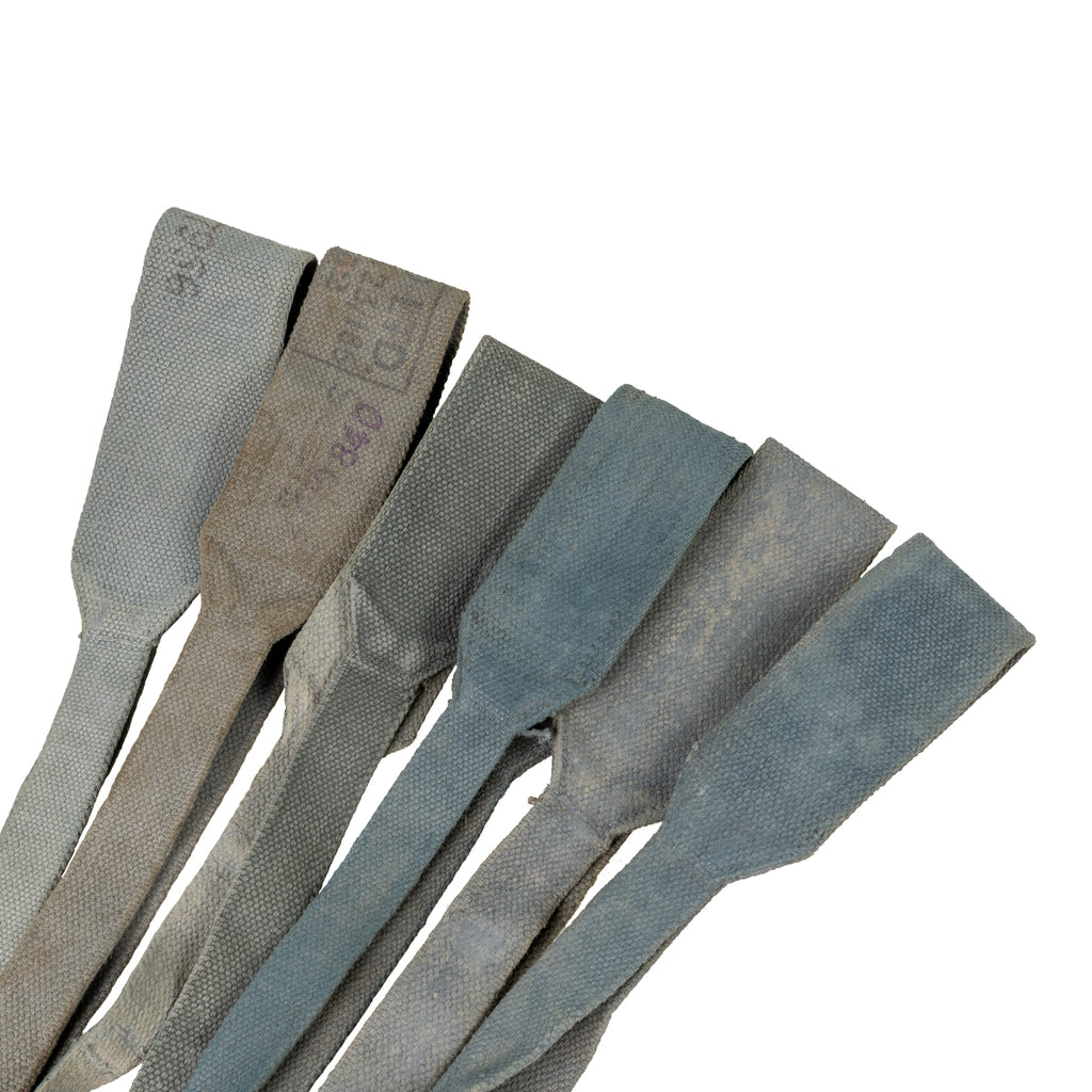 Collection of grey and weathered 37 Pattern canvas straps showing variations in color and military use.
