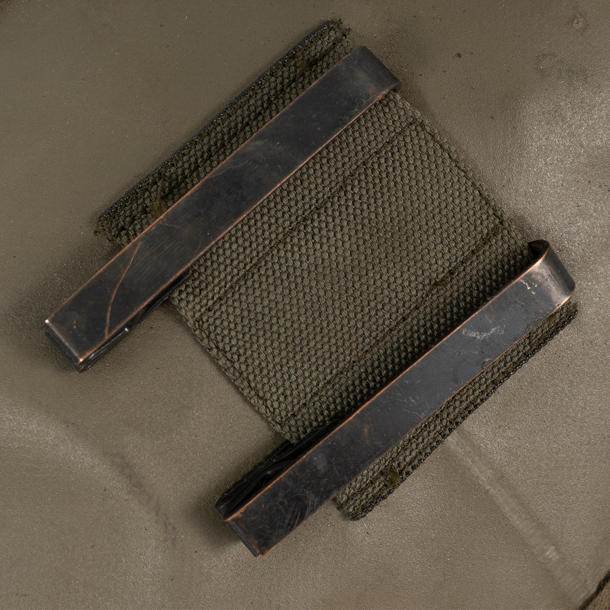 Macro shot of the sturdy M1910 metal wire keepers on the back of the PVC cover for mounting to combat gear and packs.