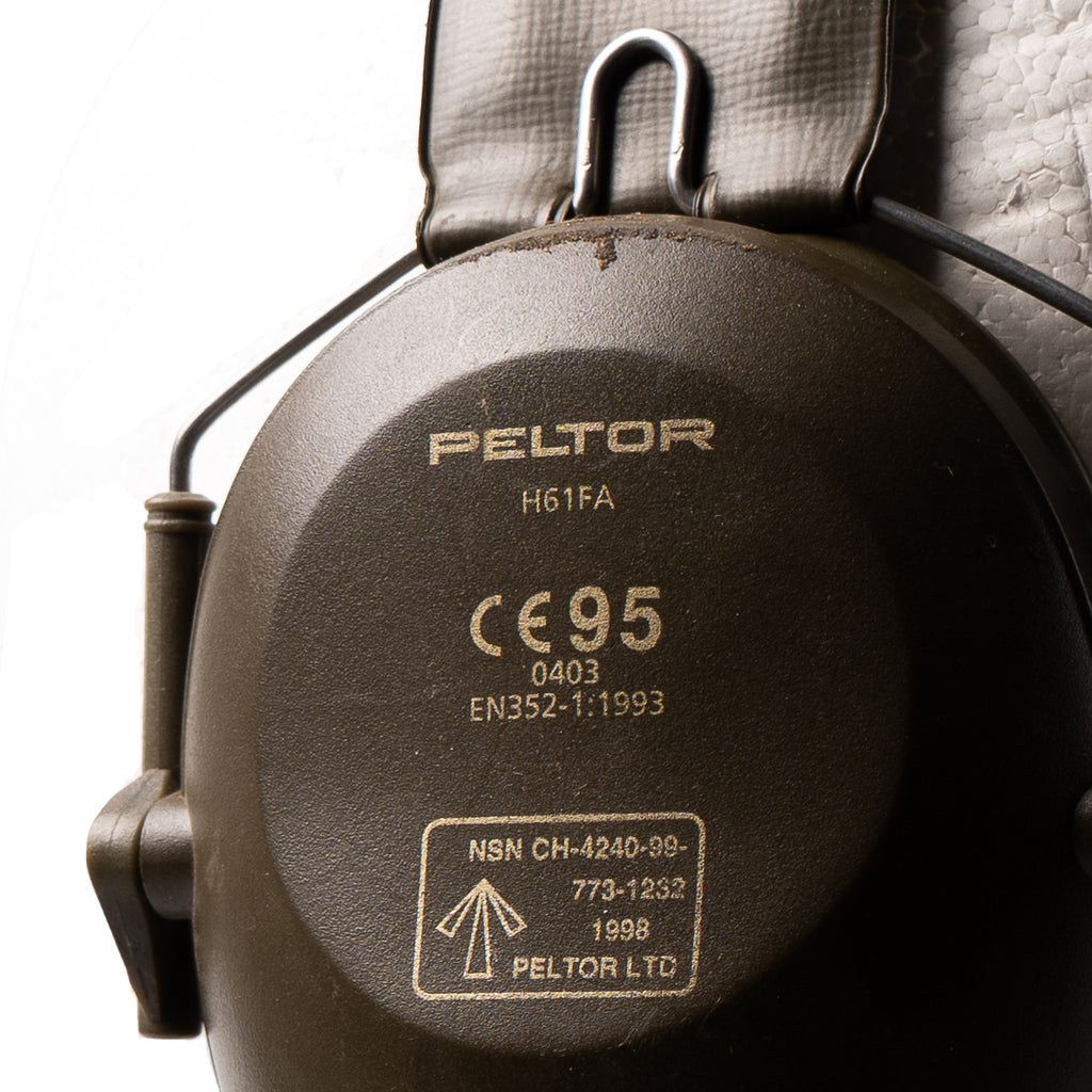 Close-up detail of the Peltor H61FA ear cup stamp, featuring the British NSN 4240-99-773-1232, 1998 production date, and military broad arrow marking.