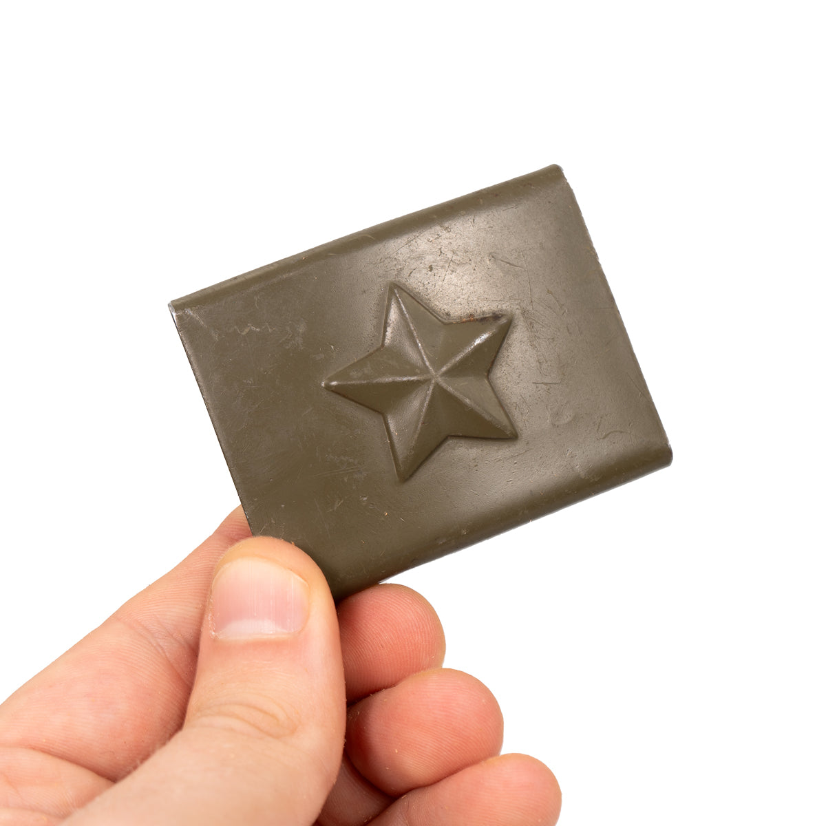 Hand holding the military-issue olive-drab metal belt buckle featuring a distinct raised star detail.