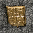 Macro shot of the detailed golden Czechoslovakian cockade emblem mounted on the grey faux fur front of the surplus Ushanka hat.