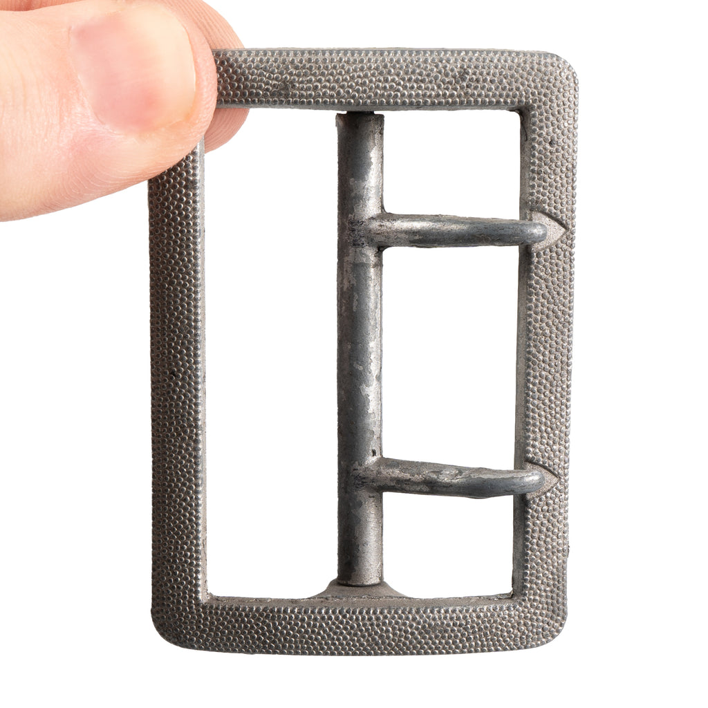 Hand holding the WW2 German Officer's aluminum claw buckle, highlighting the two-prong design and size.