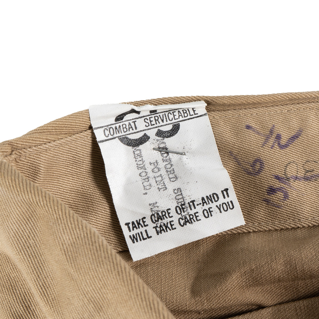 Interior view of a WW2 Garrison Cap with the 'Combat Serviceable' tag and slogan printed on white fabric.