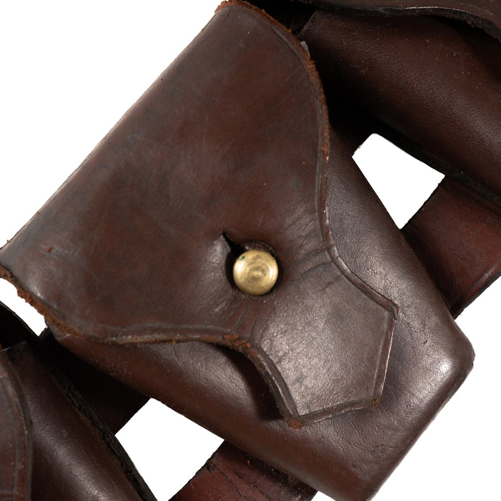 Macro detail of a single leather ammunition pocket on a Pattern 1903 bandolier, highlighting the brass stud fastener and distressed leather surface.