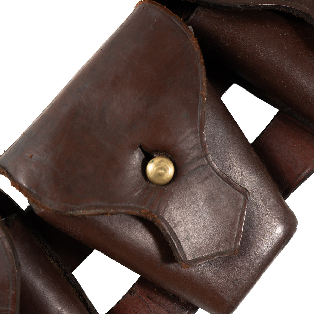 Macro detail of a single leather ammunition pocket on a Pattern 1903 bandolier, highlighting the brass stud fastener and distressed leather surface.