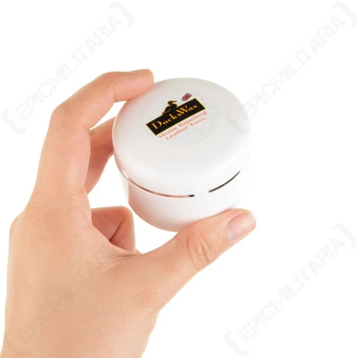 Hand holding compact 40ml tub of DucksWax clear leather waterproofing tonic