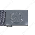 Close-up of the East German NVA belt buckle featuring an embossed hammer and compass symbol on grey metal.