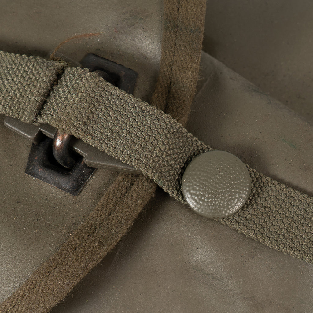 Close-up of the textured olive green strap fastener and button closure on the shovel's protective carrying case.