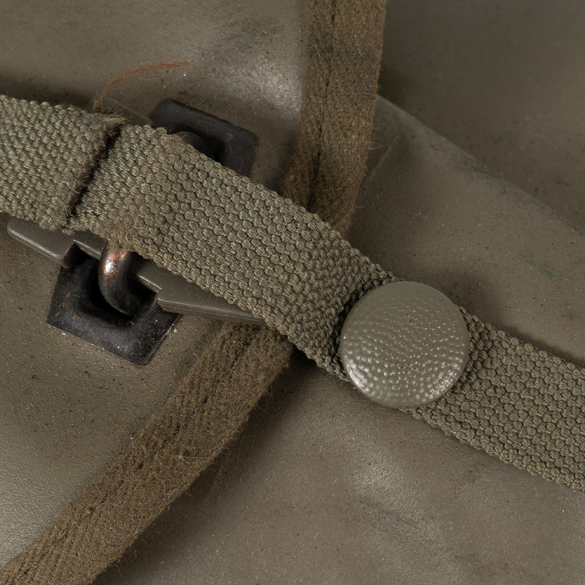 Close-up of the textured olive green strap fastener and button closure on the shovel's protective carrying case.