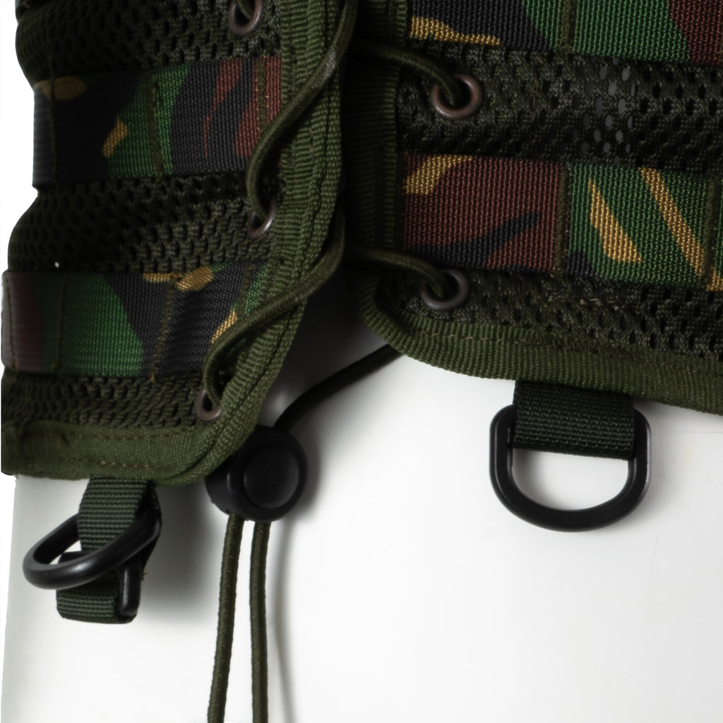 Detail view of the side lacing system with D-ring attachment points on the lower edge of the woodland camo vest.