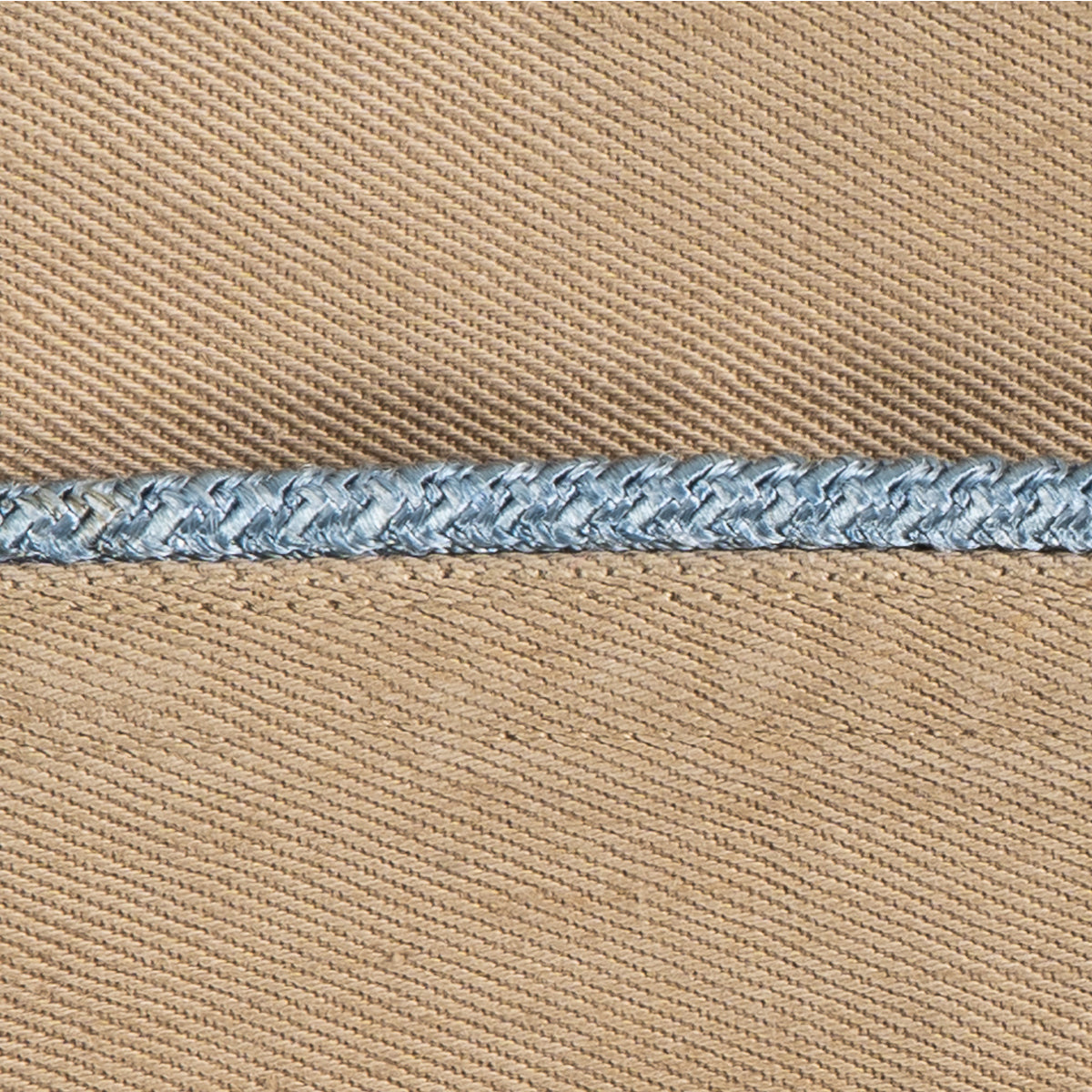 Macro detail of a vintage Khaki Garrison Cap featuring blue braided piping against tan cotton twill fabric.