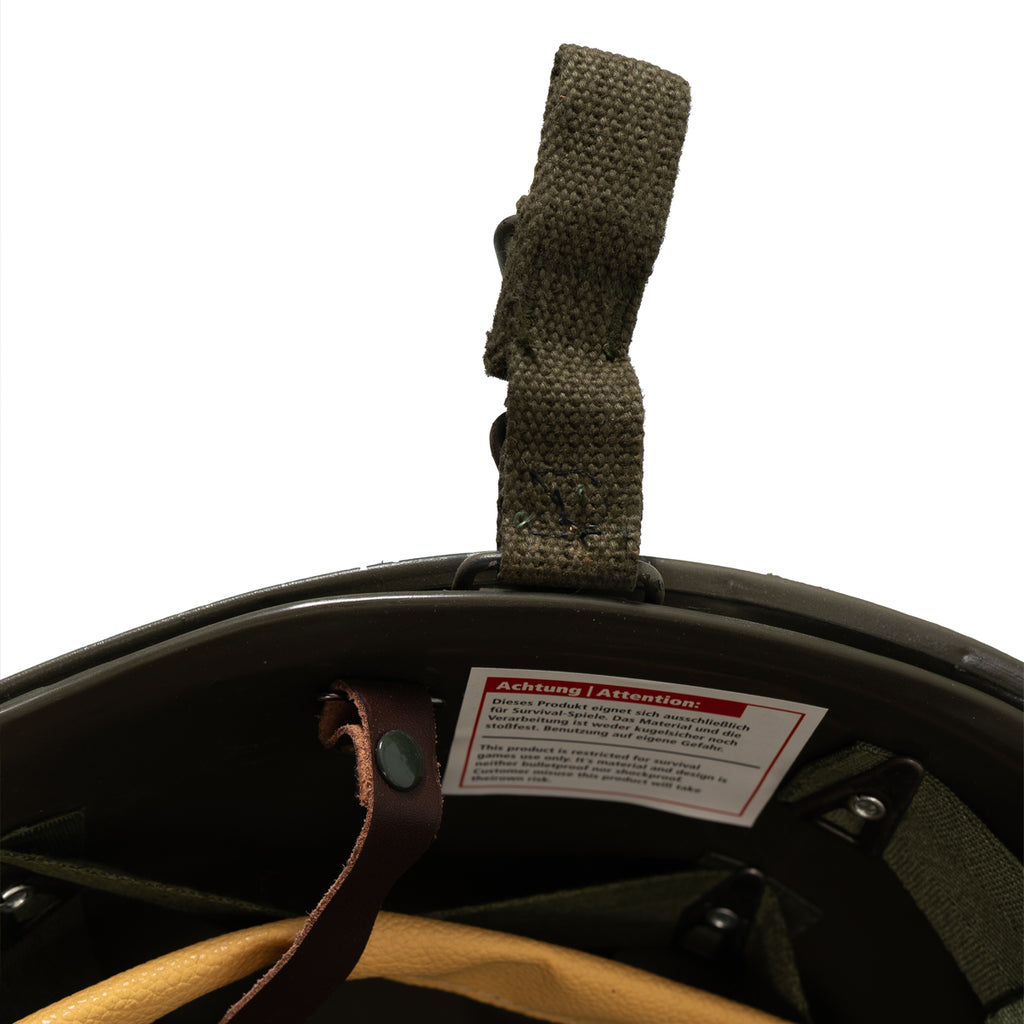 Interior detail of the M1 style helmet featuring a safety warning label on the plastic liner.