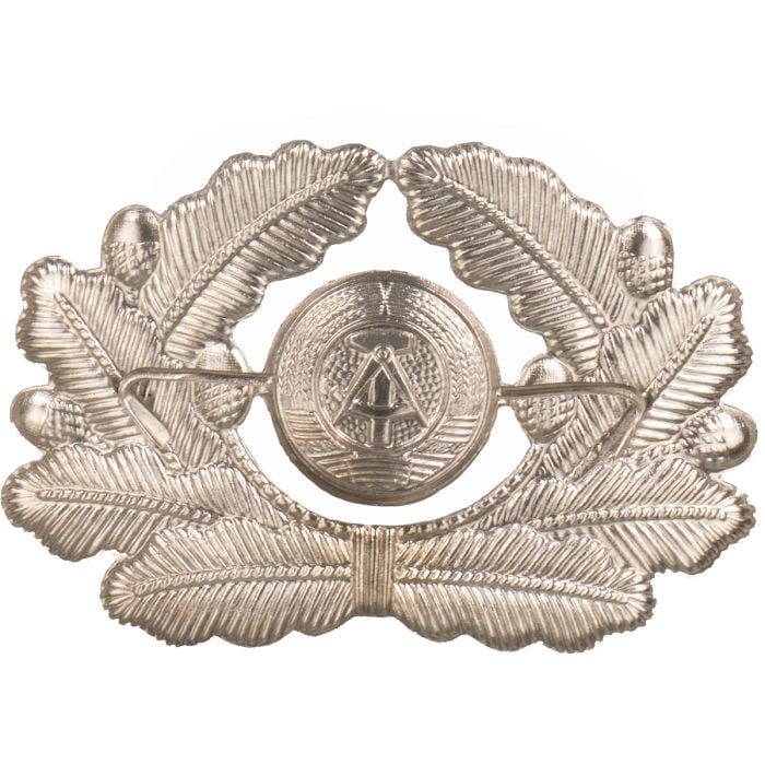 Rear view of East German NVA officer visor cap badge showing flat dual metal attachment prongs