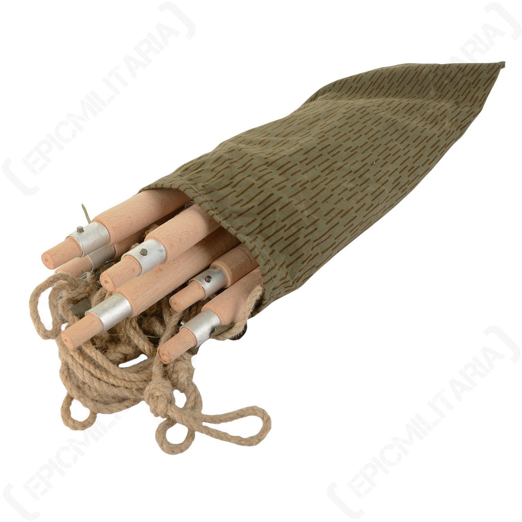 Close-up of the East German Zeltbahn pole kit partially packed inside its distinctive strichtarn camouflage fabric pouch with natural cordage.