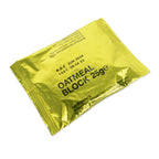 Angled top-down view of a 25g British military oatmeal ration block sealed in lightproof gold laminate foil showing ingredients and BBE date.