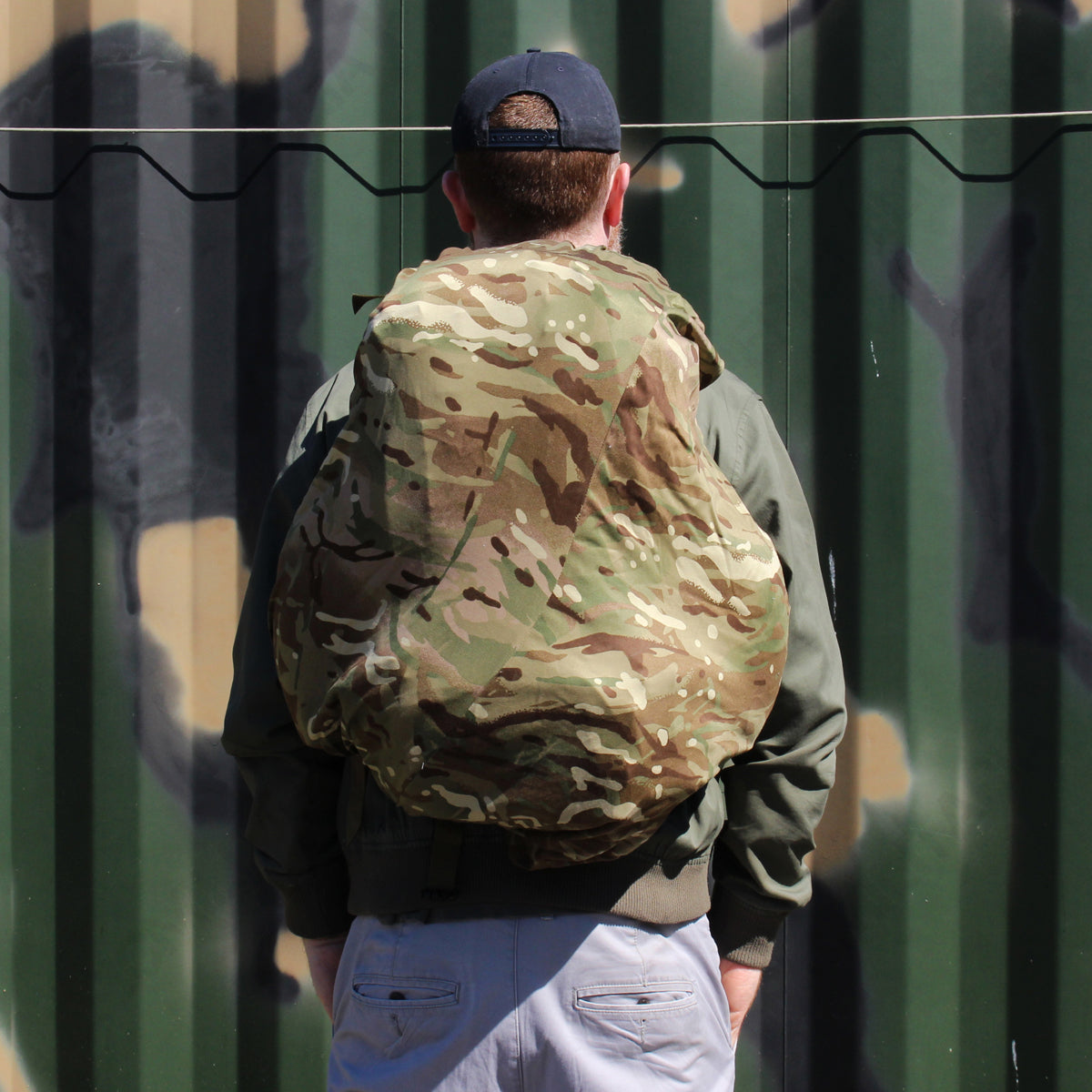 Rear view of a person wearing a civilian daypack fully concealed by a genuine British Army MTP camouflage cover.