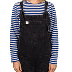 Female model styling striped Russian Telnyashka shirt under black denim dungarees