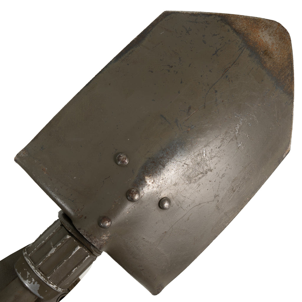 Detail view of the steel shovel head with visible wear, rivets, and textured locking collar for secure field positioning.