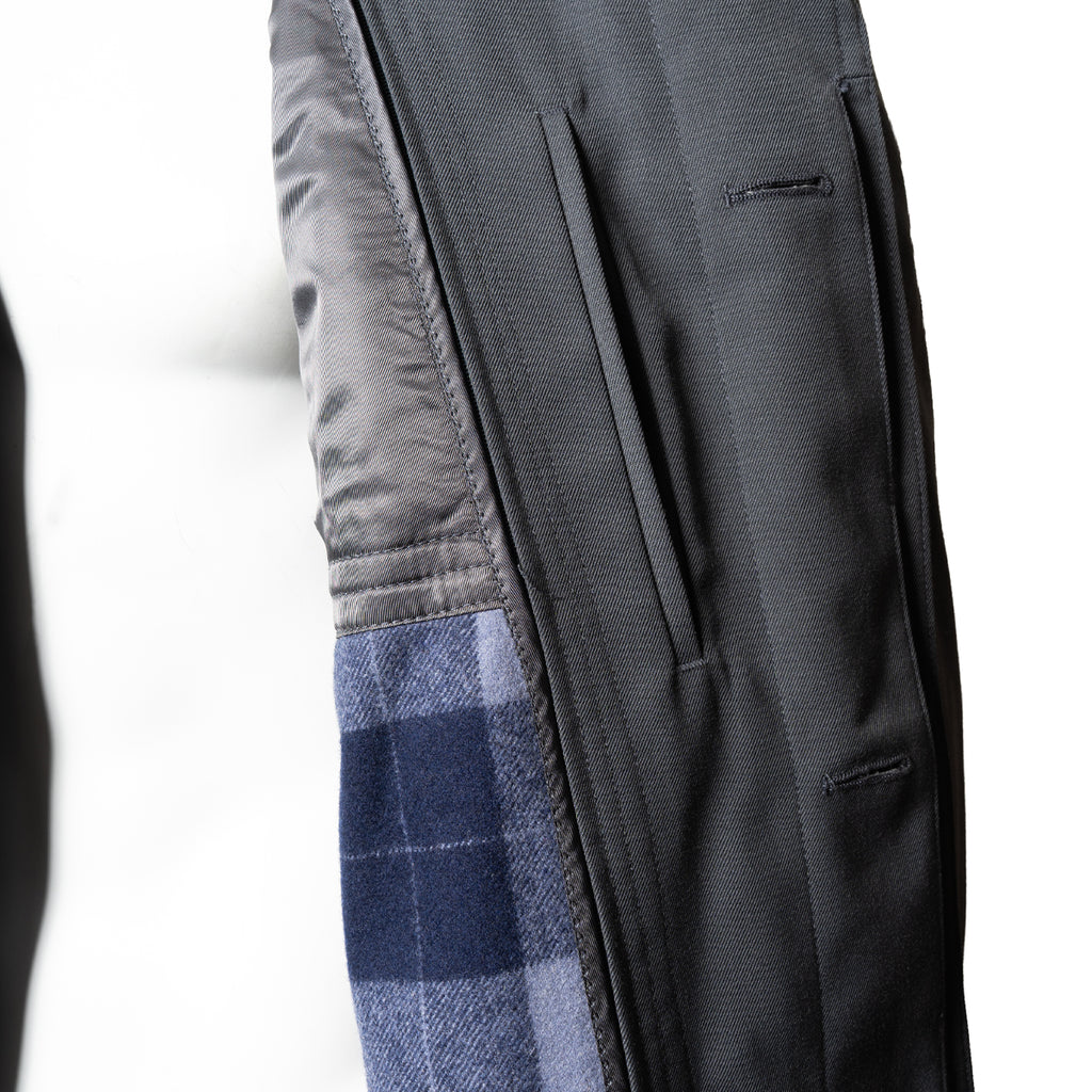 Close-up of the coat interior, revealing the distinctive blue and grey plaid wool lining and button-front construction.