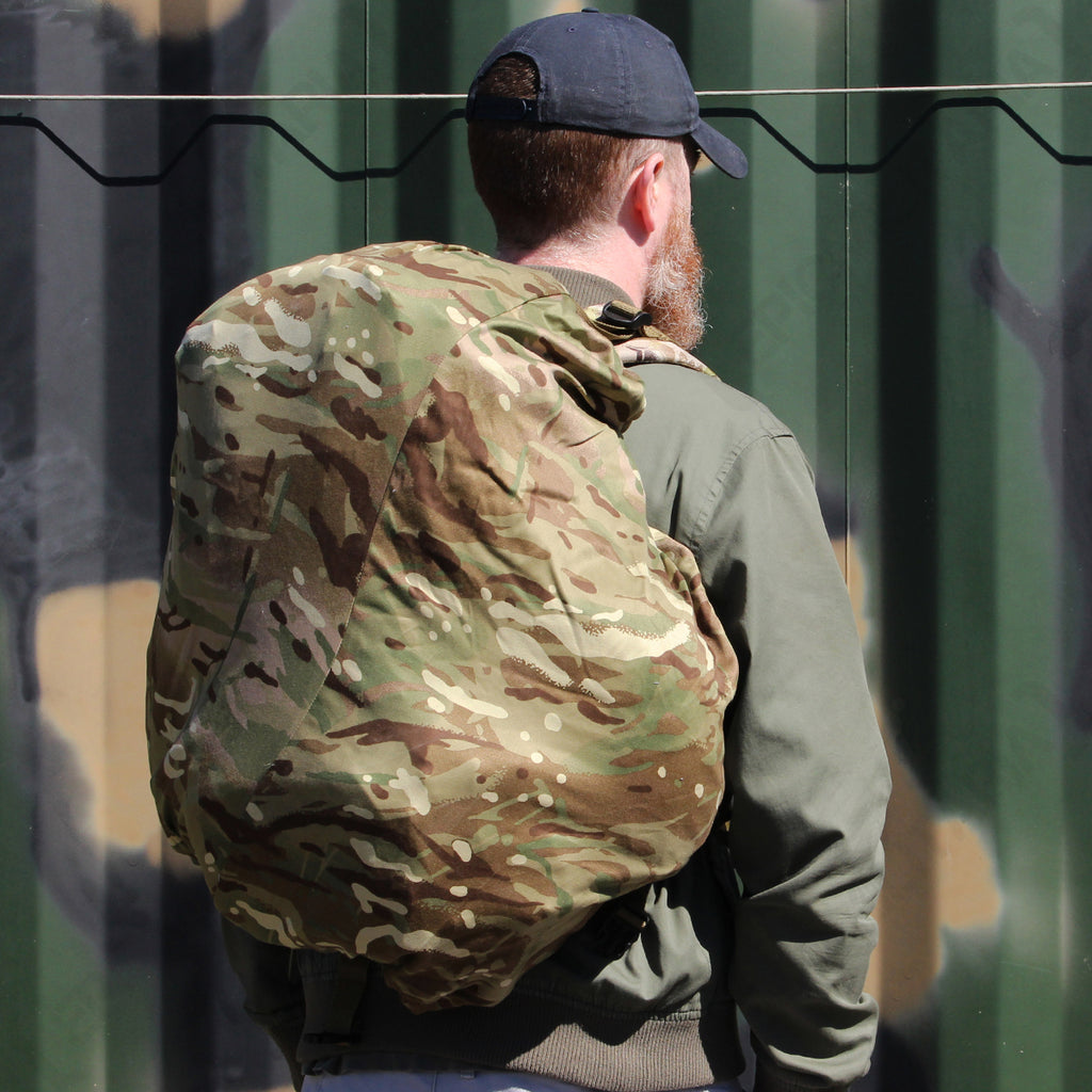 Close-up side view of a person wearing a daypack protected by an MTP camouflage cover, showing the secure elasticated fit.