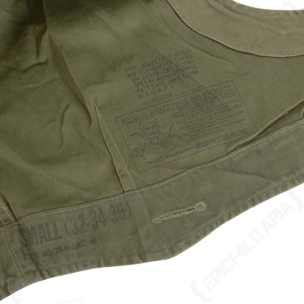 Close-up of the interior of an original M43 hood, displaying stamped military markings including size Small 32-34-36 and stock number details.
