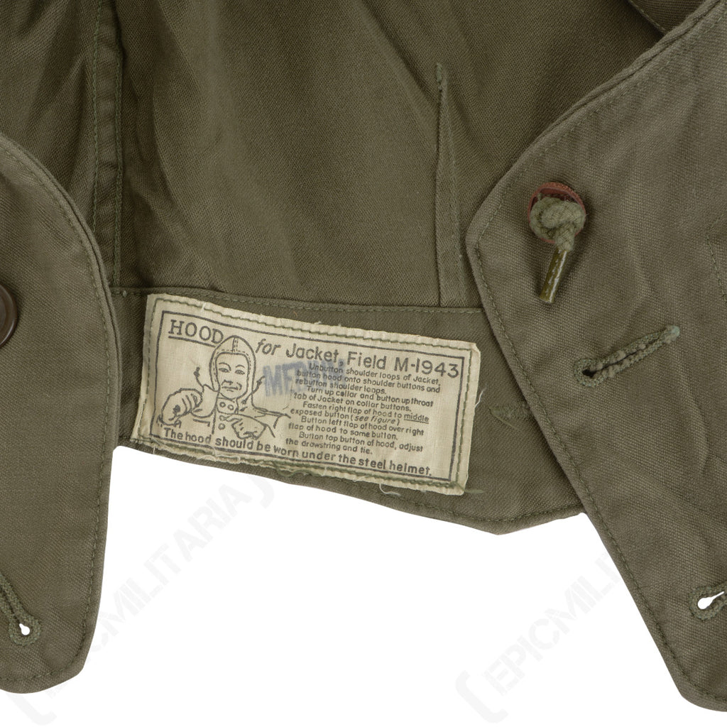 Close-up of the official WWII US Army M43 field jacket hood laundry tag with original printed instructions and military branding.